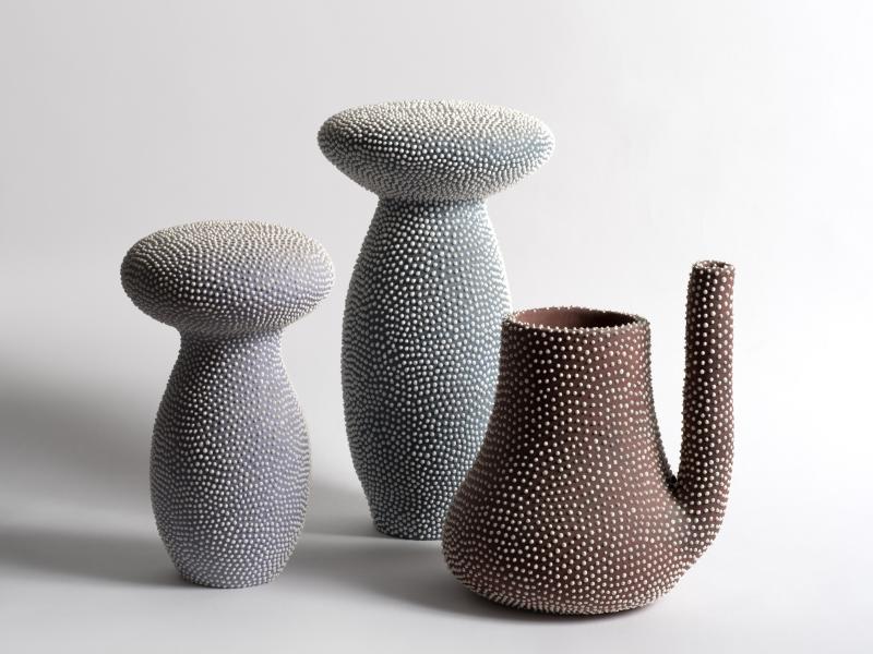 to svampelignende keramiske figurer og en kande ses mod en enkel hvid baggrund