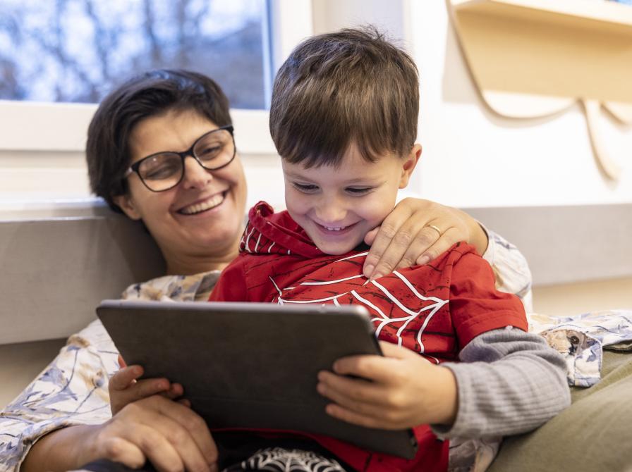 Barn og voksen sidder med tablet